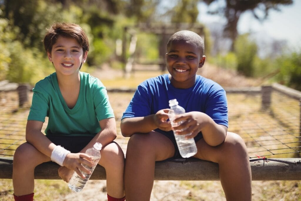 Two boys laughing and drinking water